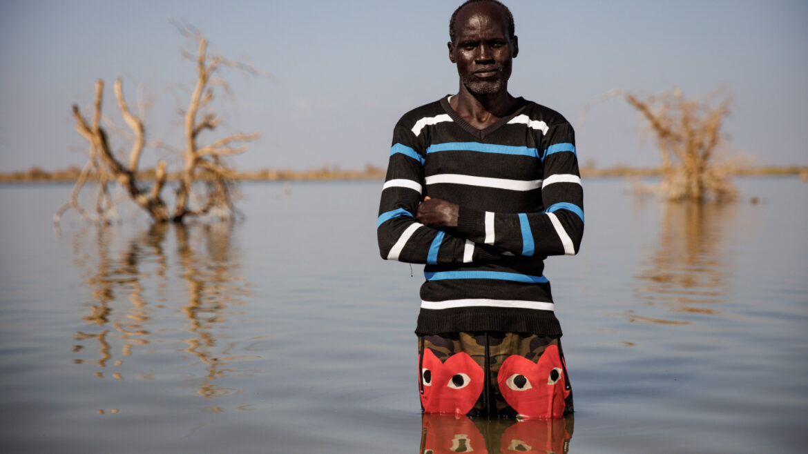 A South Sudanese displaced by floods stands in a submerged village
