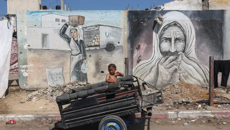 A mural in central Gaza shows a Palestinian woman carrying flour and a hungry man